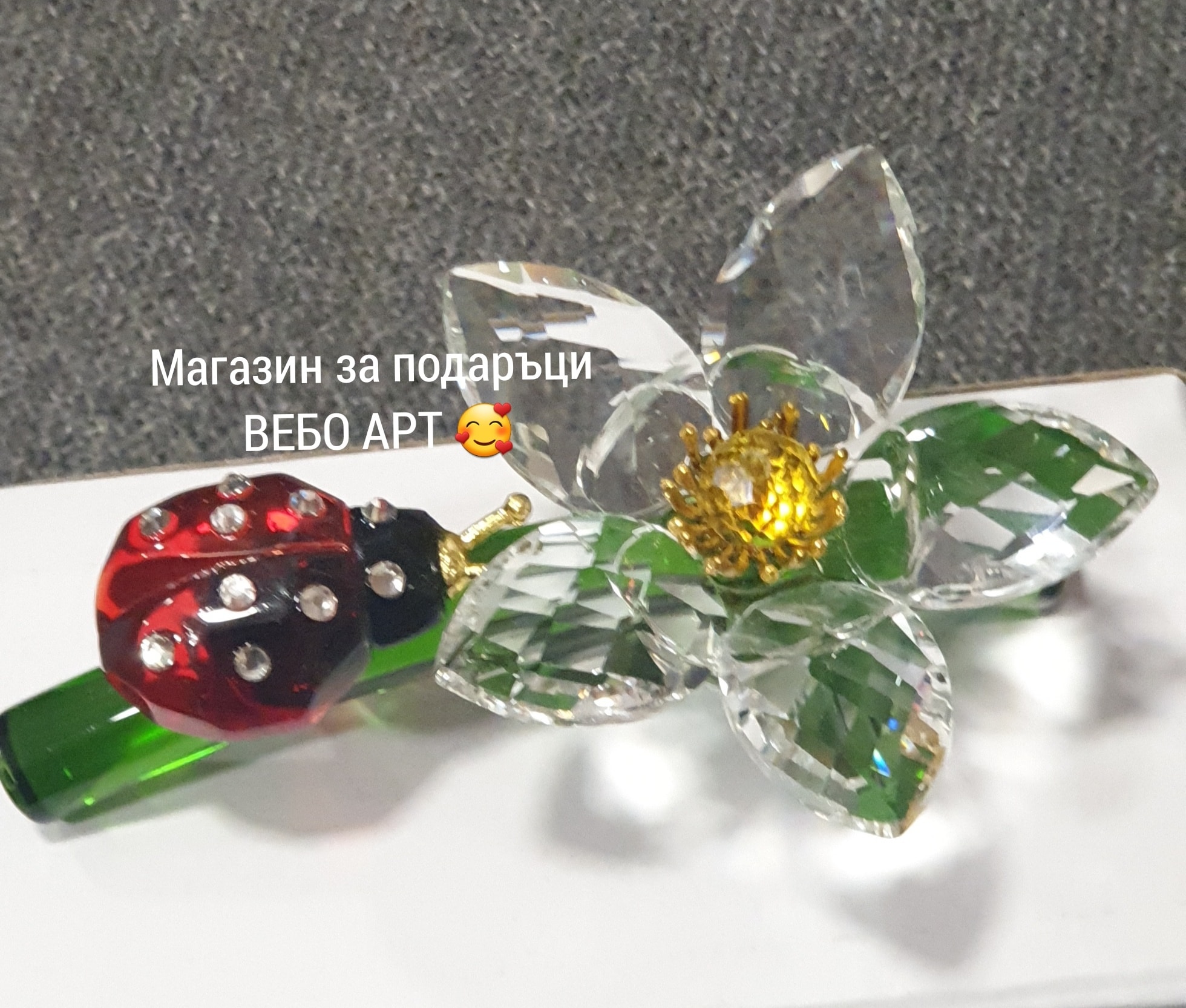Цвете от кристално стъкло в бял цвят върху зелена клонка, и калинка